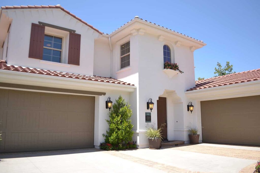Mediterranean-style house with a terracotta roof, shutters, and plants at the entrance.